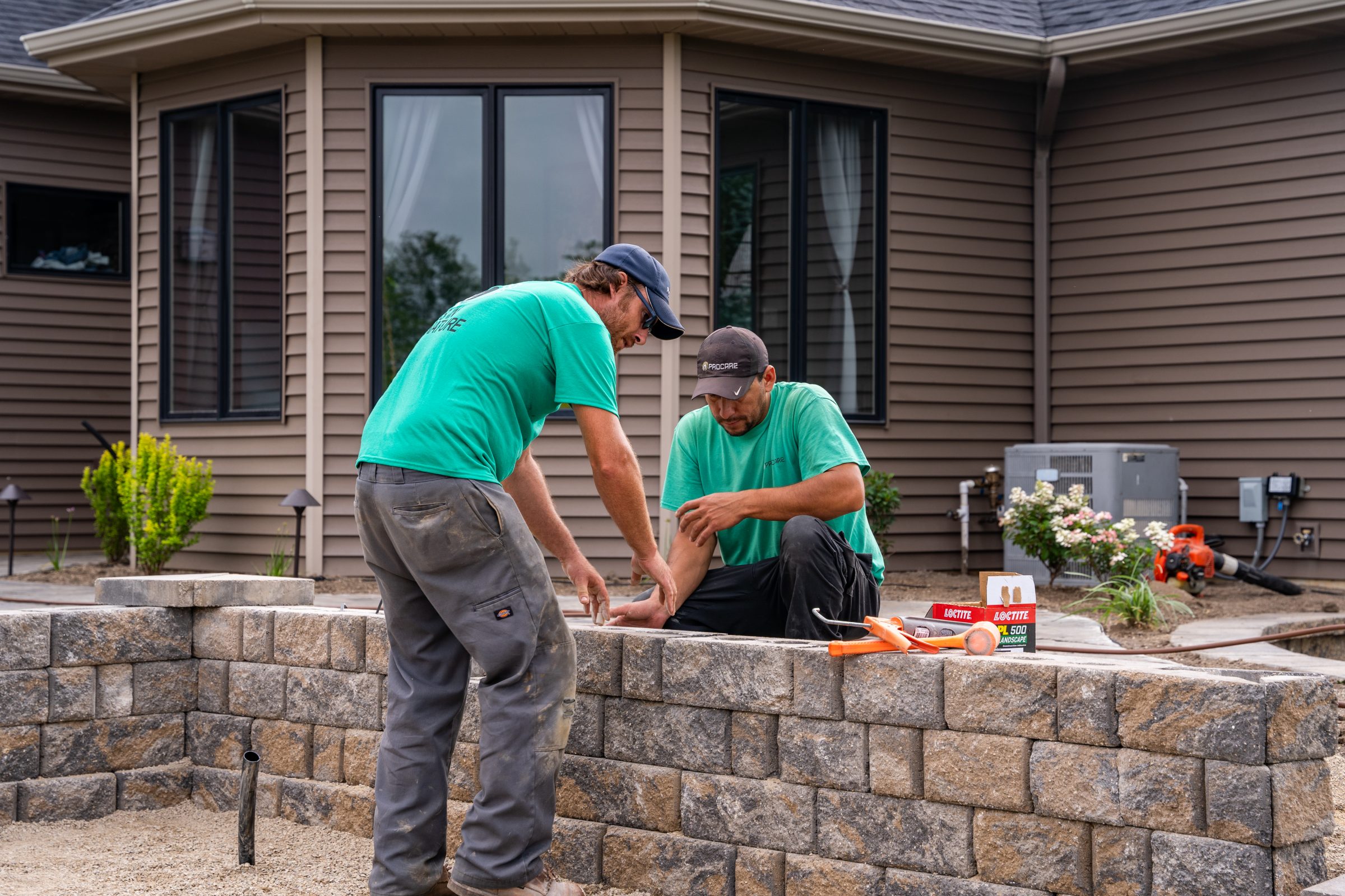 Two workers building a stone garden wall