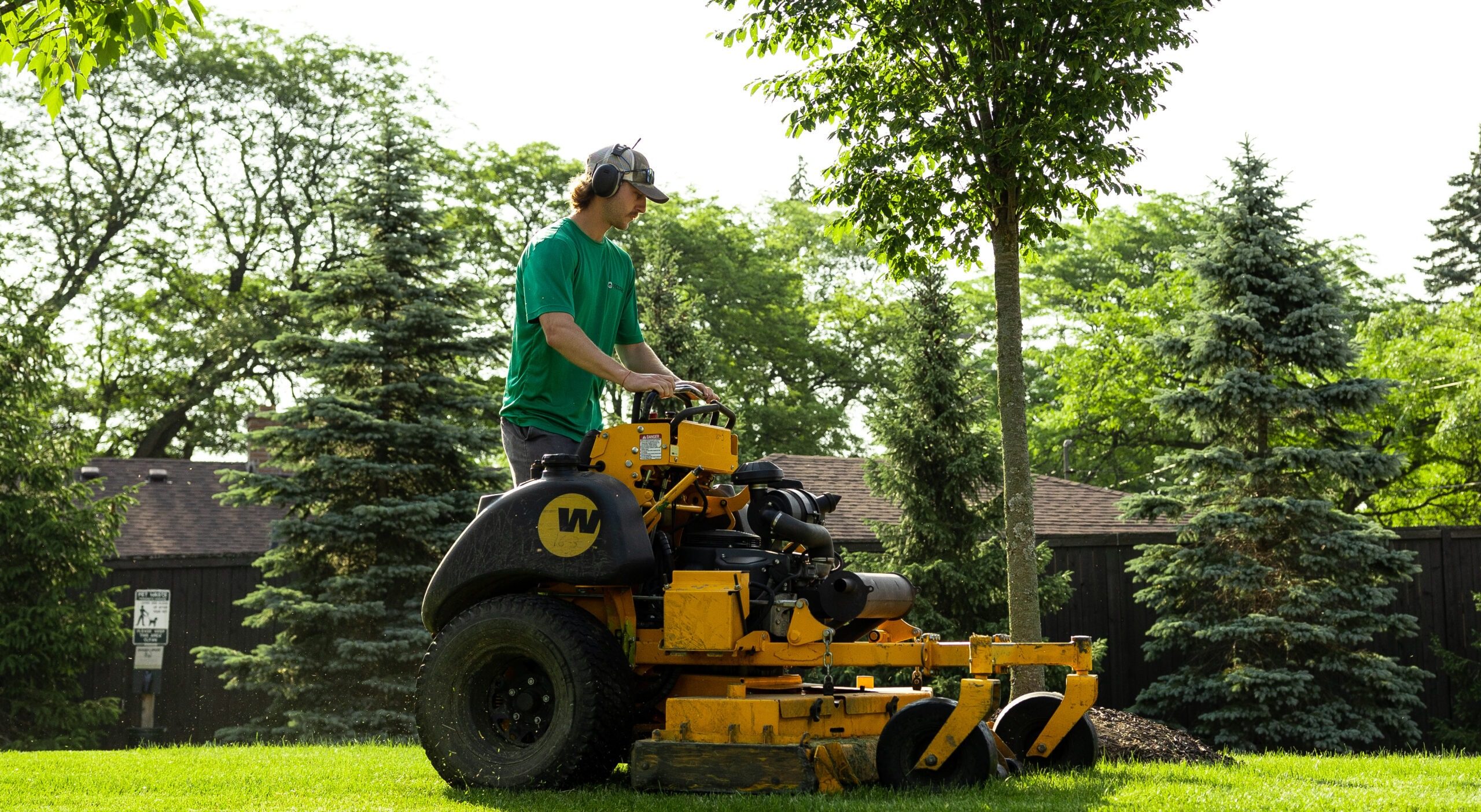 Man mowing lawn with riding lawnmower.