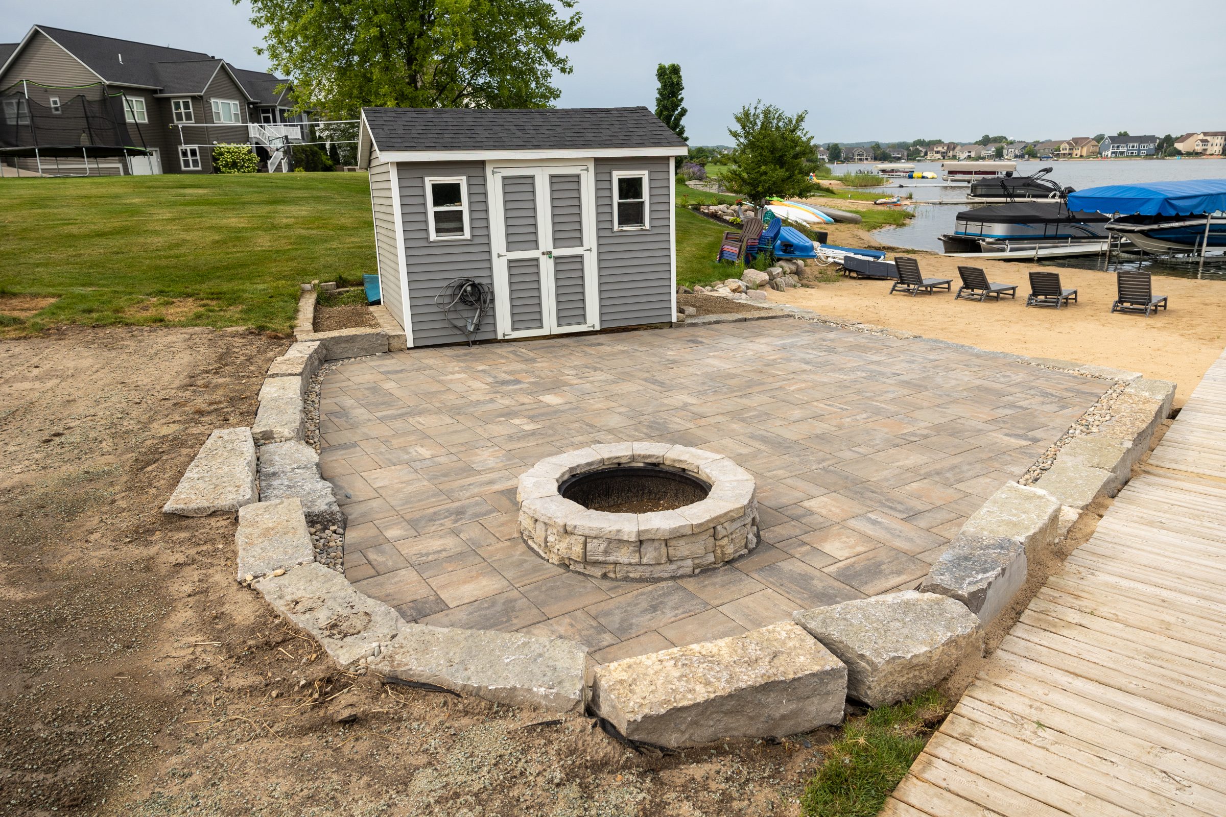 Lakeside patio with fire pit and boathouse.