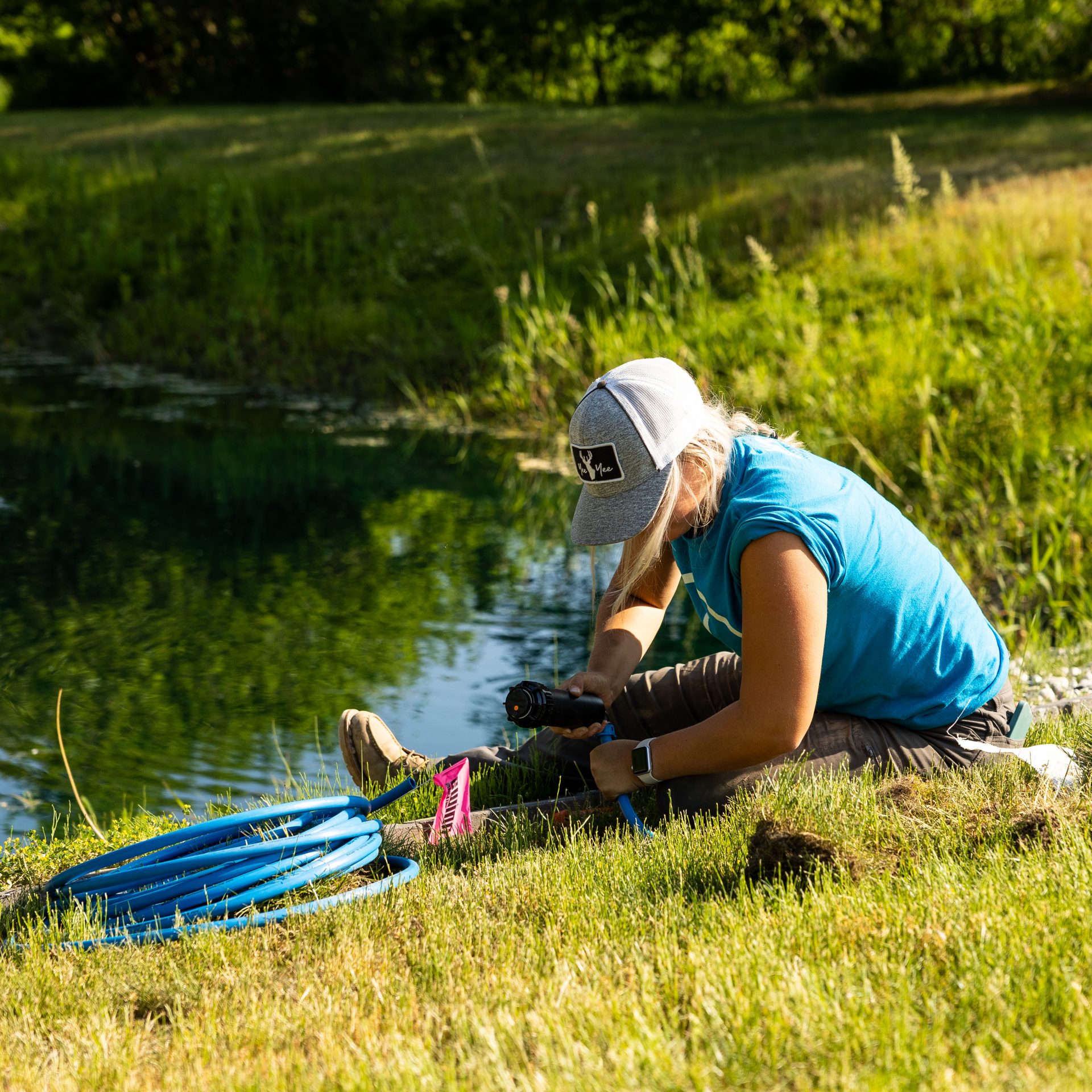 Person working with hose by a pond.