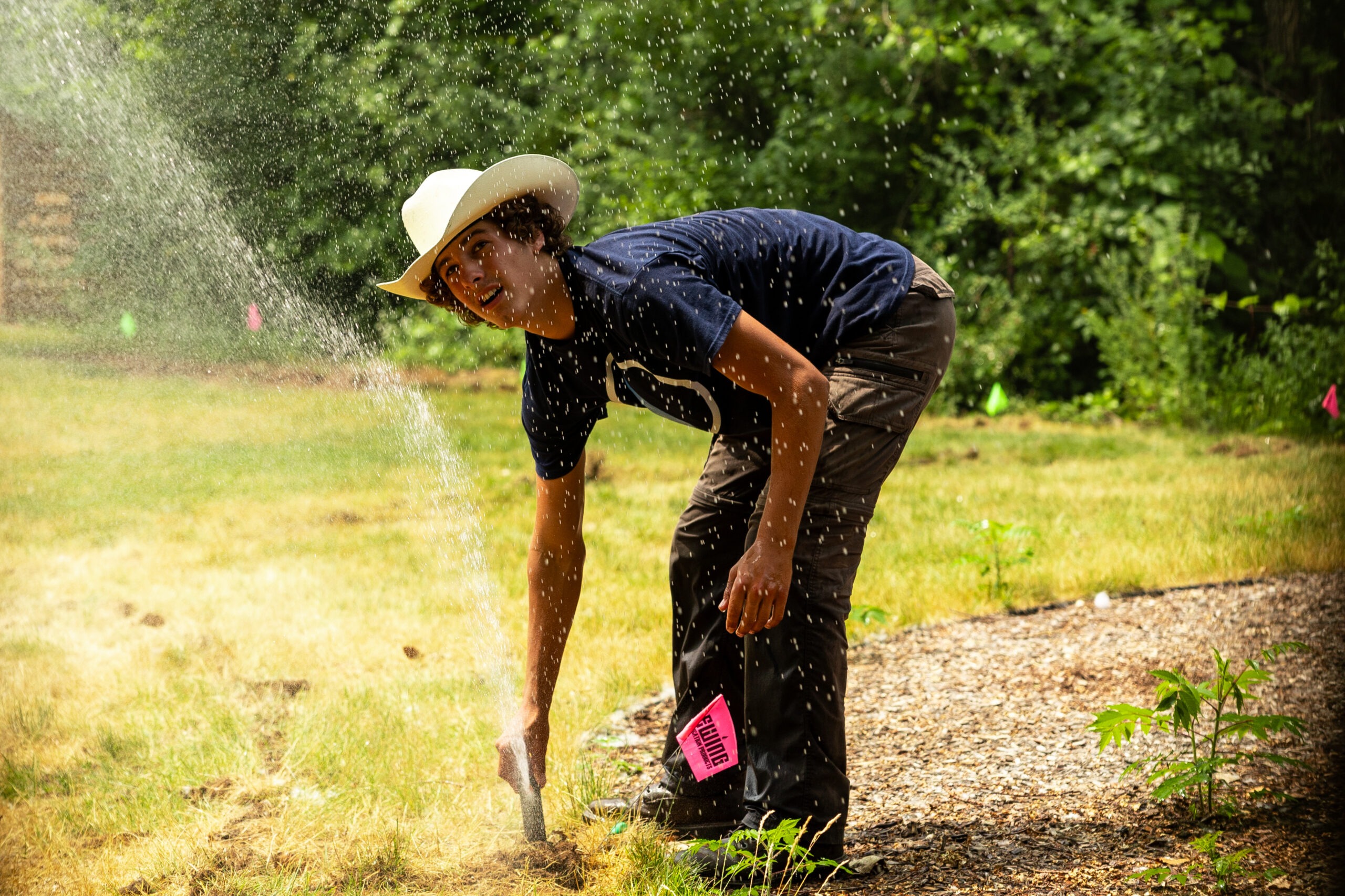 Person adjusting garden sprinkler on sunny day