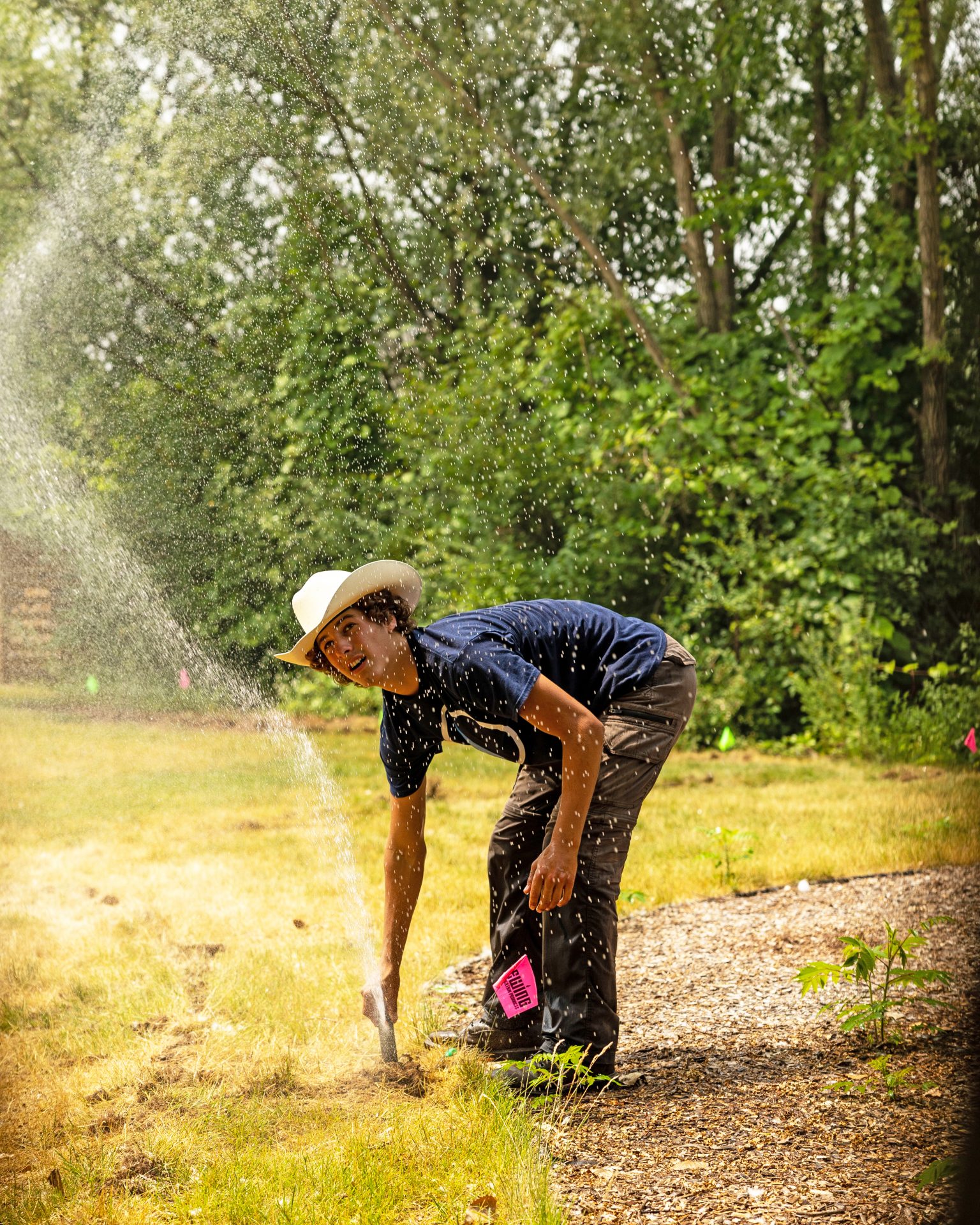 Person adjusting sprinkler in sunny garden