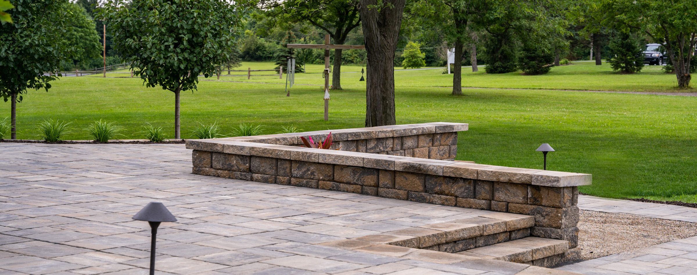 Stone patio with lush green lawn and trees.