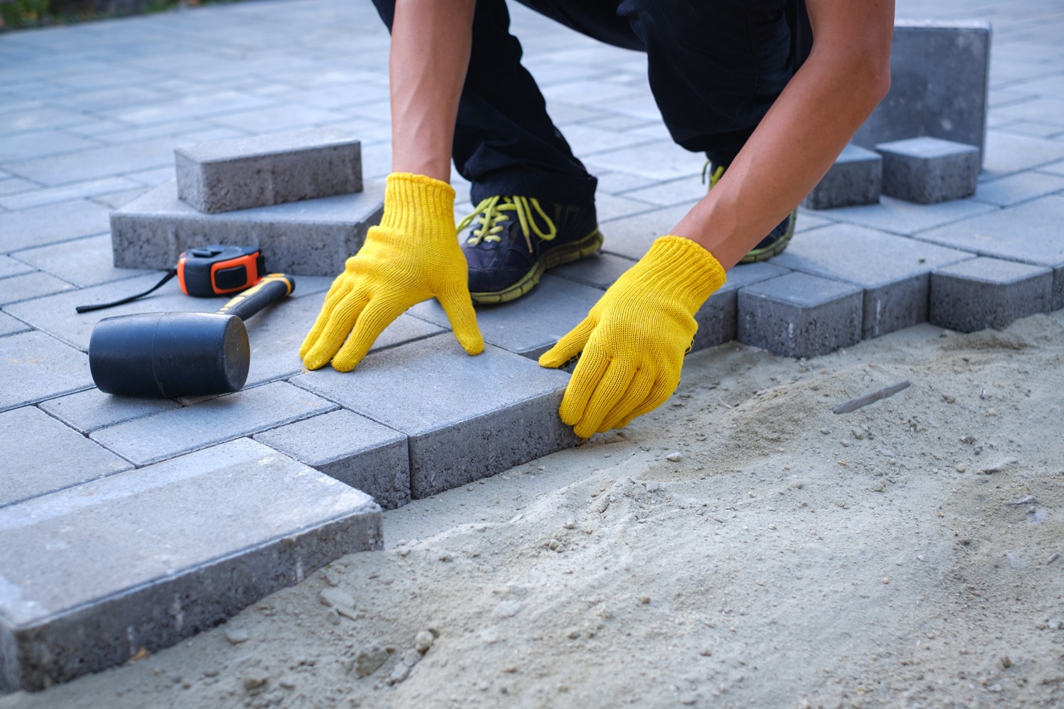 Laying paving stones with yellow gloves.