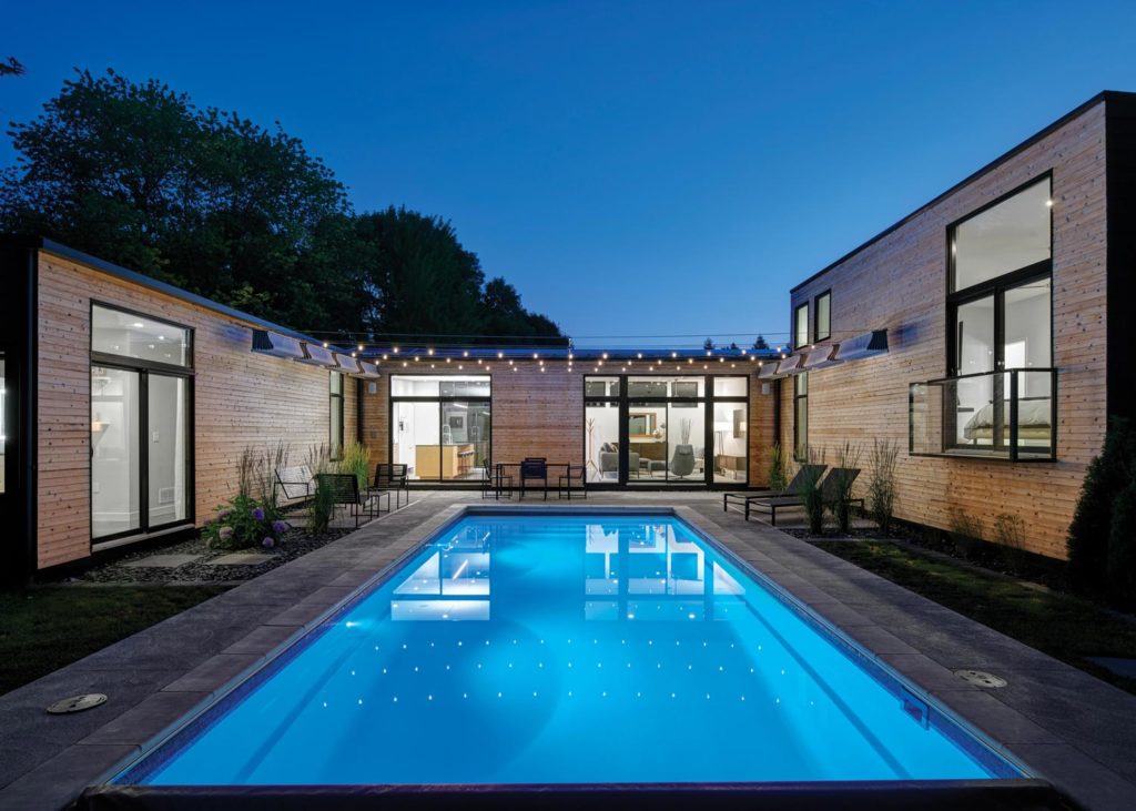 Modern house with illuminated outdoor pool at night.