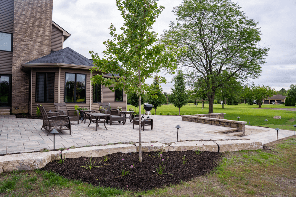 Spacious patio with furniture and lush garden.