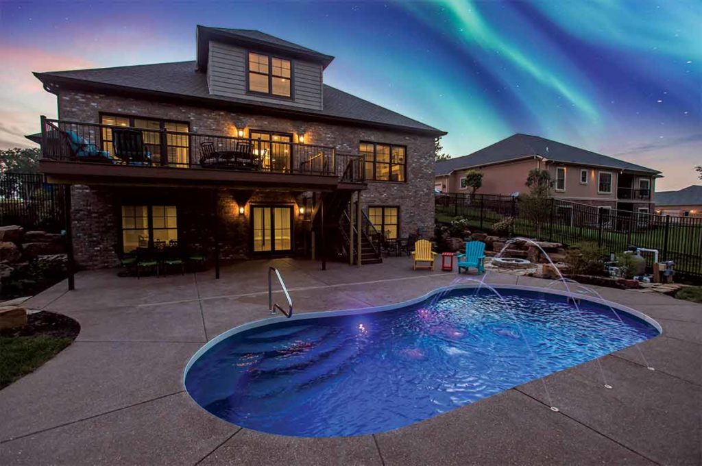 Backyard pool with northern lights visible at dusk.