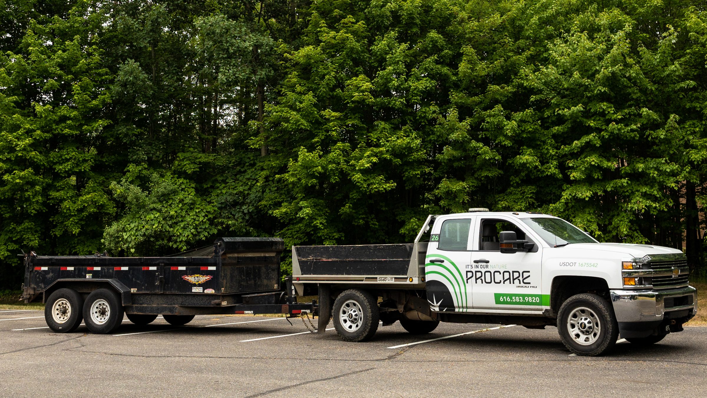 Pickup truck with trailer in parking lot near trees.
