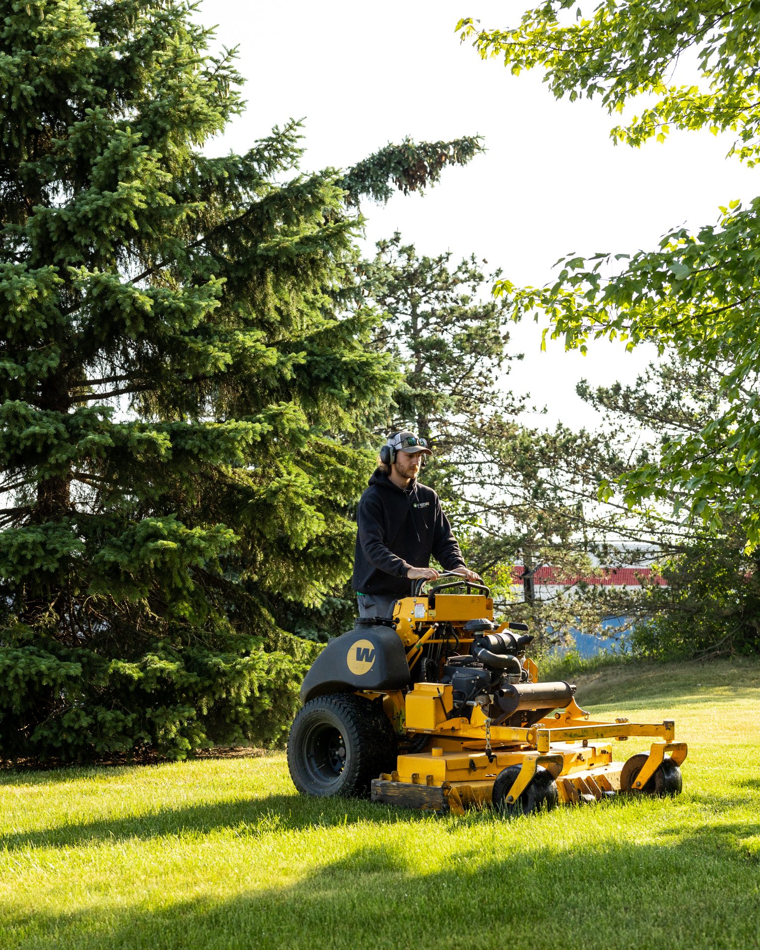 Person mowing lawn with yellow ride-on mower