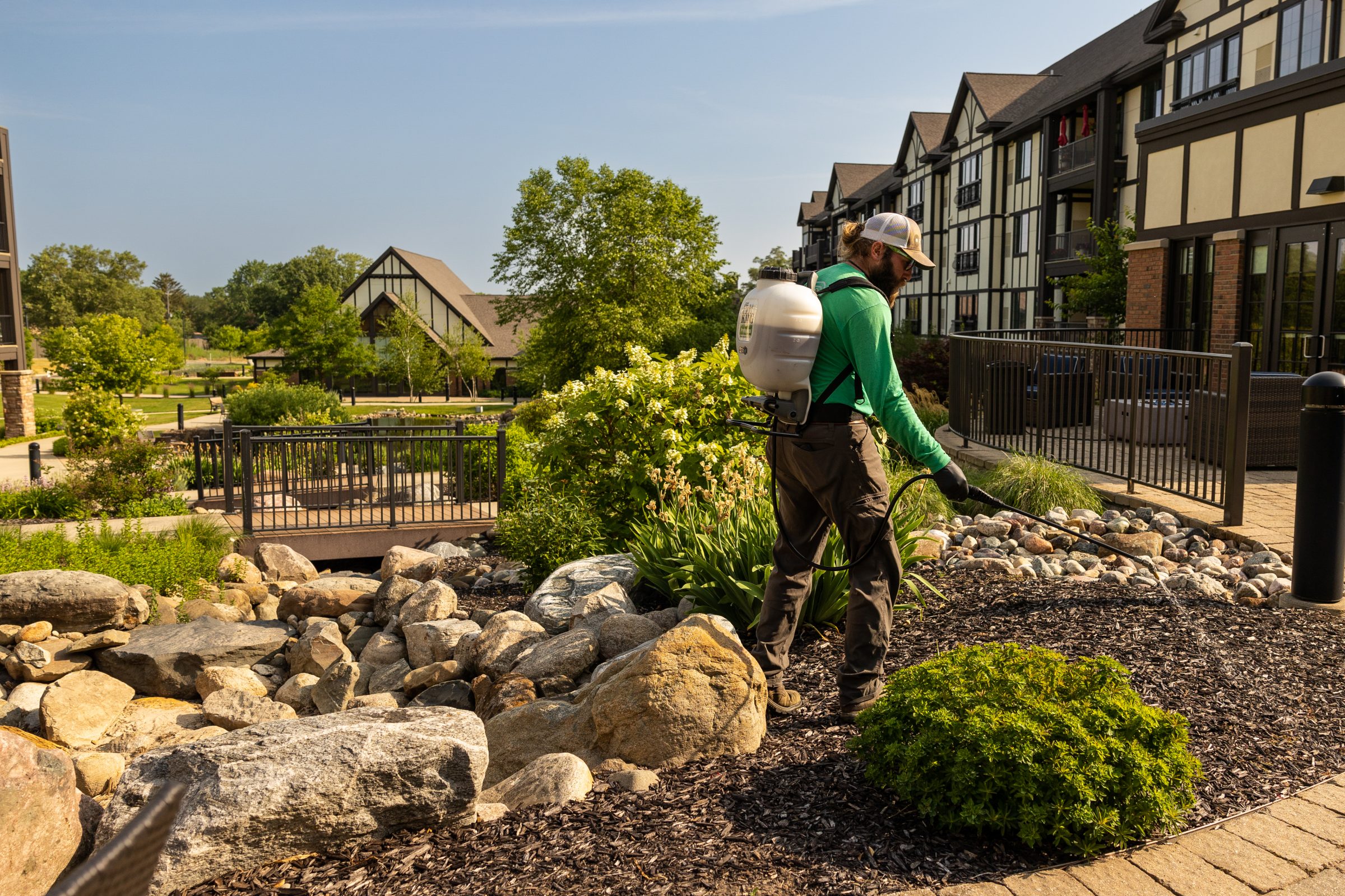 Gardener watering plants in landscaped outdoor area.