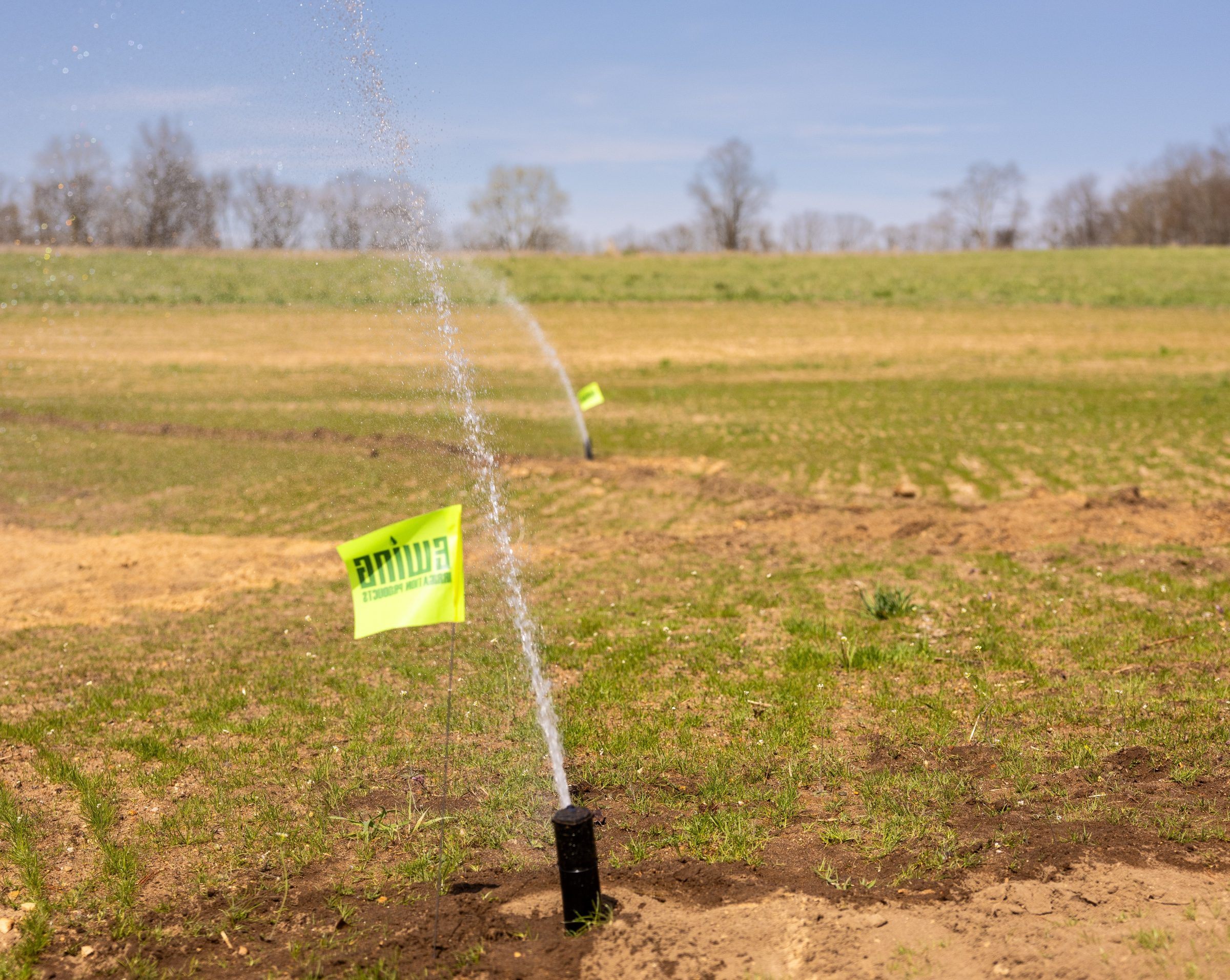 Field irrigation system sprays water on grass.