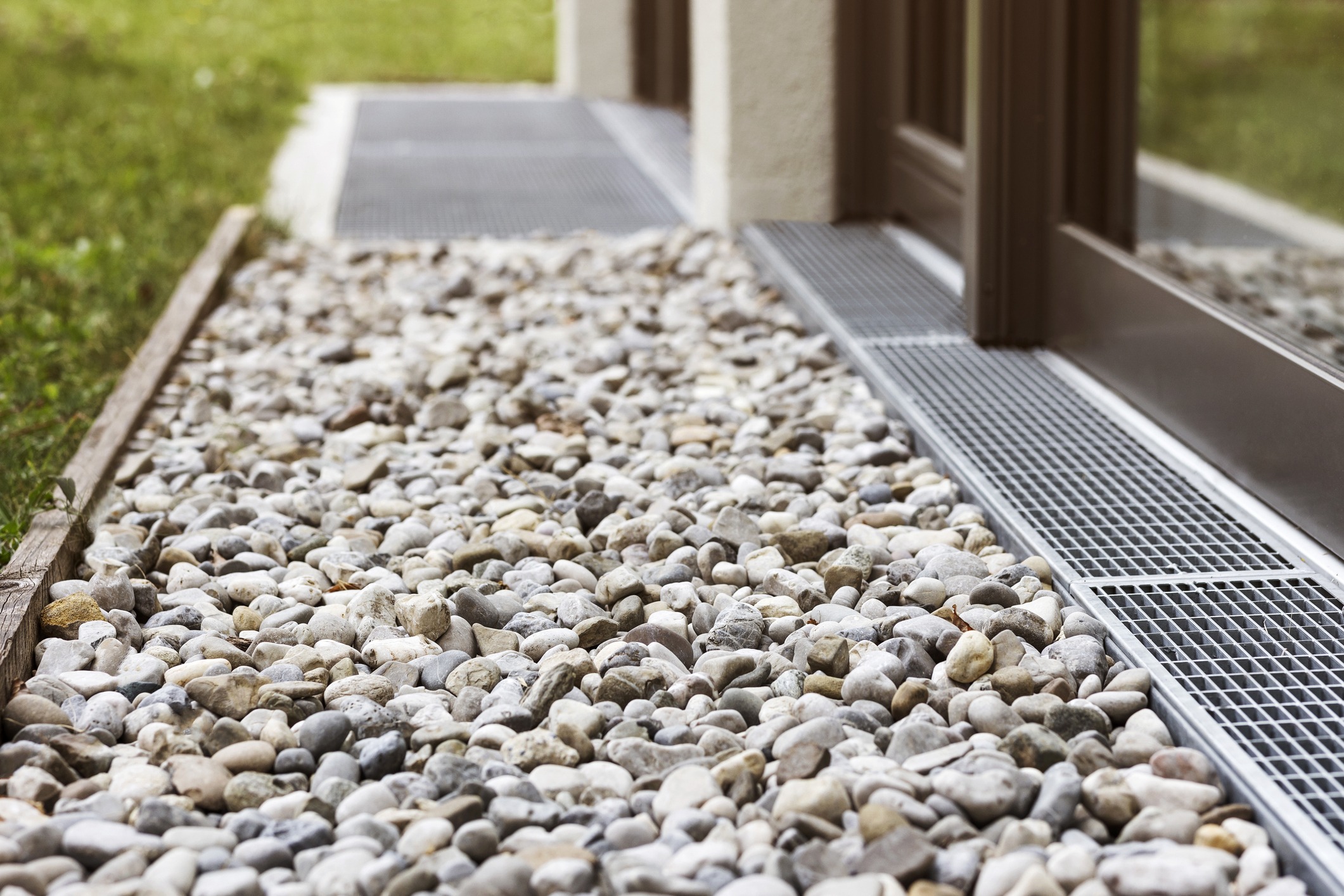 Pebbled walkway beside brown door with metal grating.
