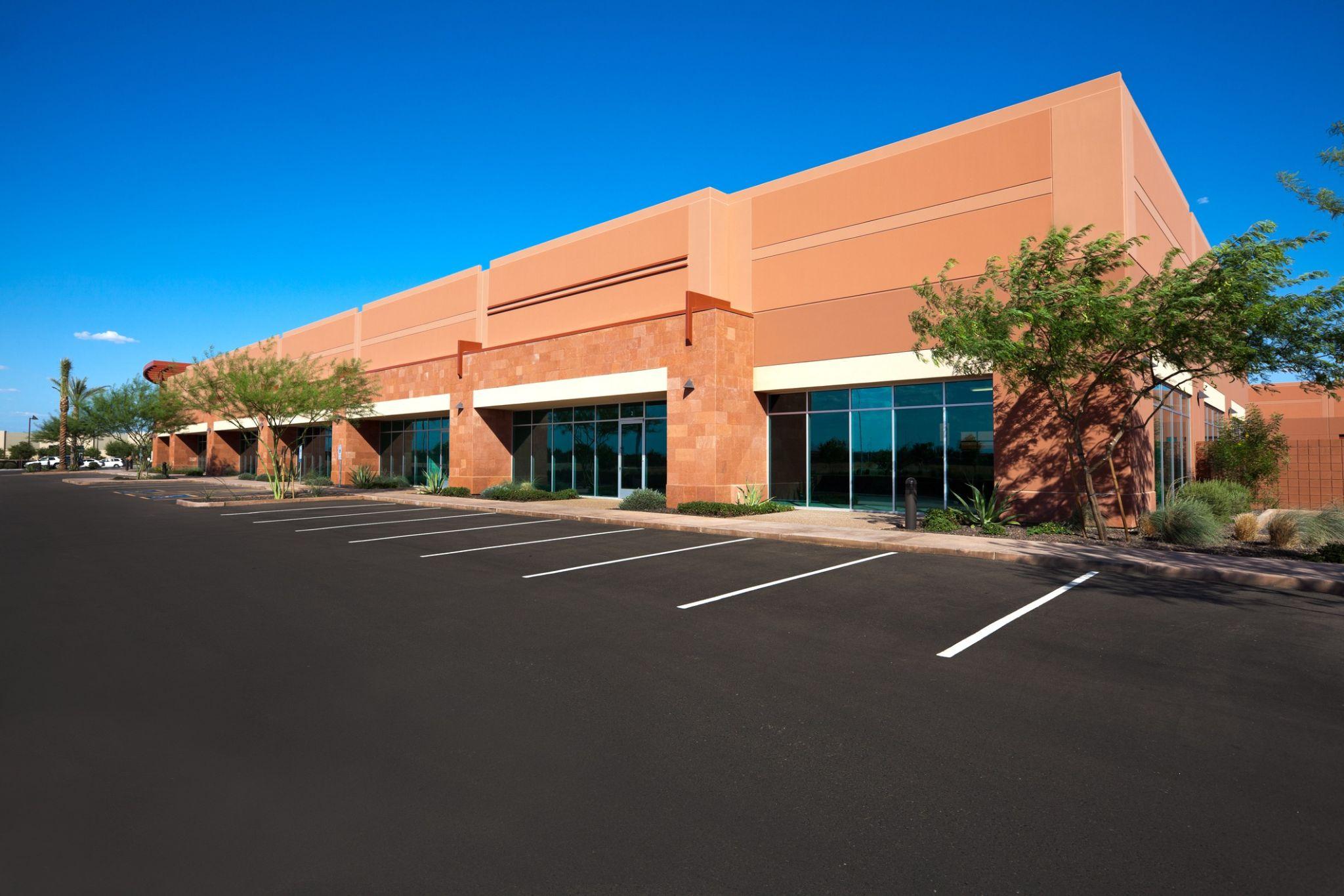 Empty commercial retail building with parking lot and desert-style landscaping