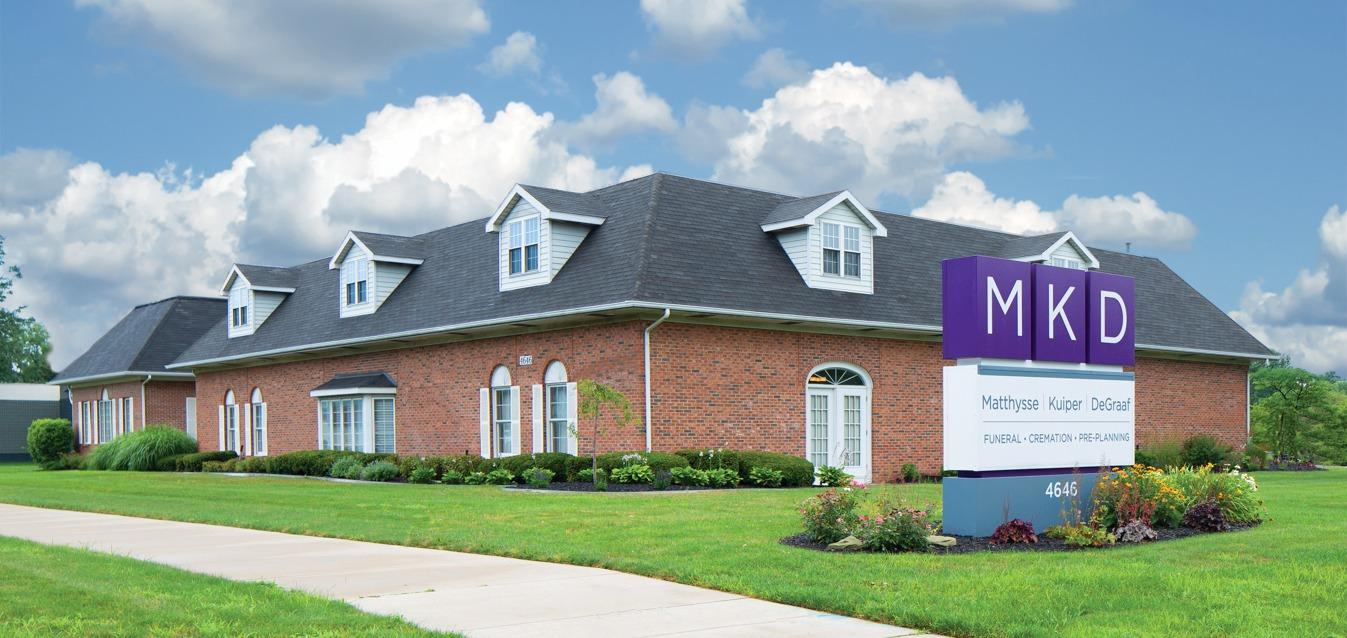 Funeral home exterior with landscaped lawn and MKD sign in front