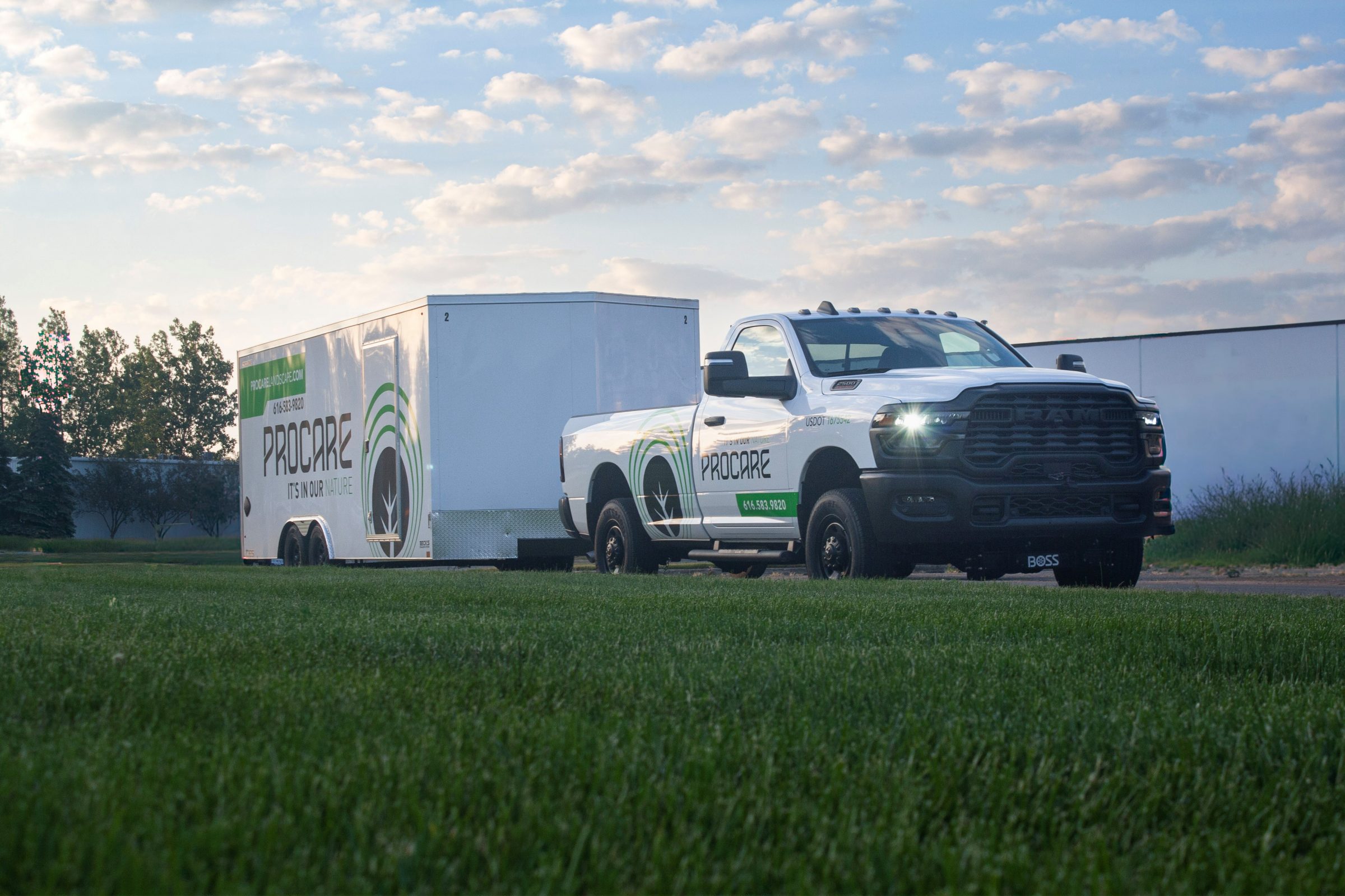 Truck towing a Procare trailer on grass field.